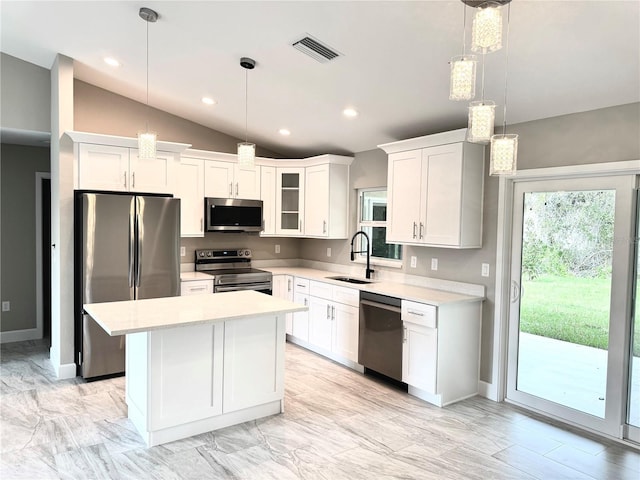 kitchen featuring hanging light fixtures, stainless steel appliances, a sink, and light countertops