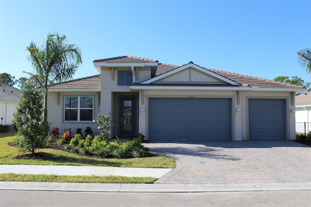 view of front of house featuring an attached garage, decorative driveway, and stucco siding