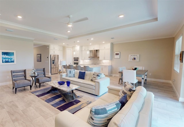 living area with a raised ceiling, crown molding, and baseboards