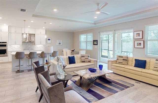 living area featuring a tray ceiling, a ceiling fan, visible vents, and recessed lighting