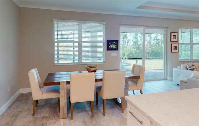 dining area with ornamental molding, a wealth of natural light, and baseboards