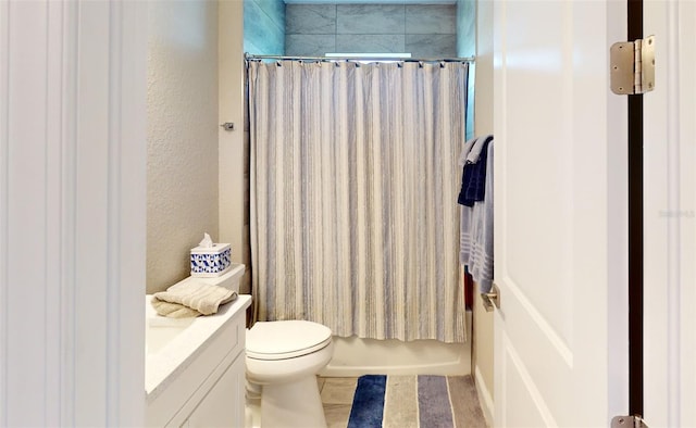 full bath with a textured wall, vanity, and toilet