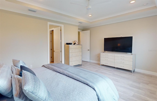 bedroom featuring light wood finished floors, baseboards, ornamental molding, a tray ceiling, and recessed lighting