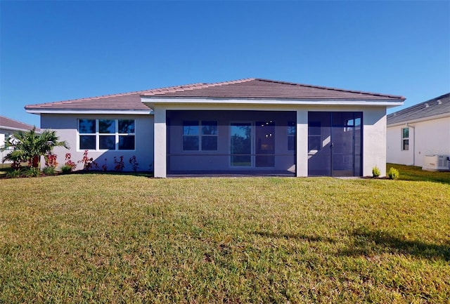 rear view of house featuring a lawn, a sunroom, and stucco siding