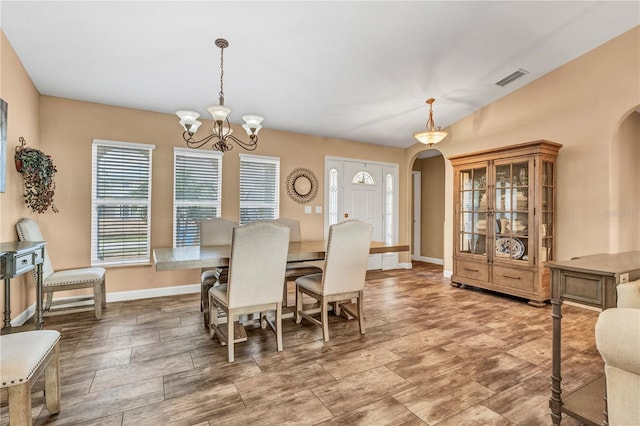 dining space featuring arched walkways, baseboards, visible vents, and a notable chandelier