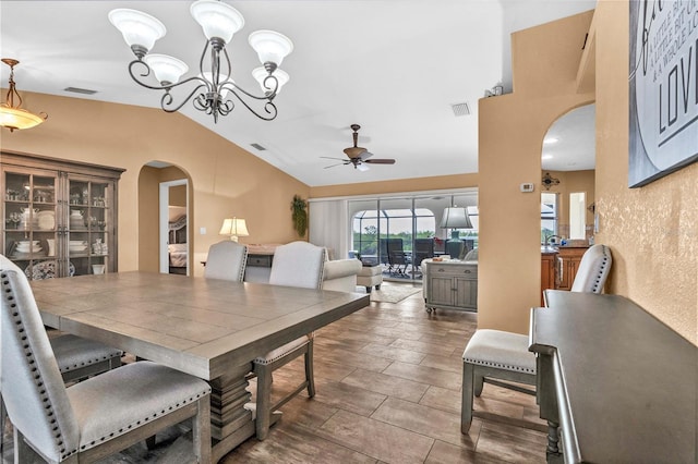 dining area with arched walkways, visible vents, vaulted ceiling, and ceiling fan with notable chandelier