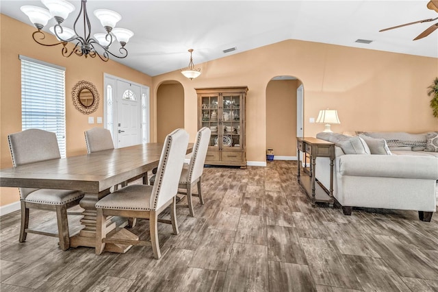 dining room featuring visible vents, arched walkways, vaulted ceiling, and wood finished floors