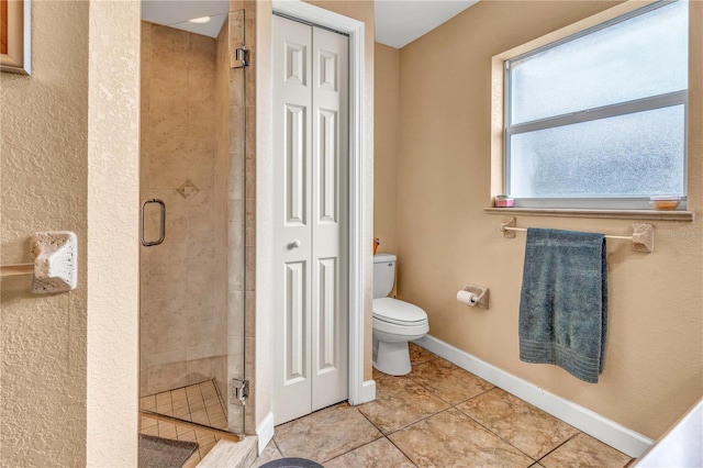 bathroom with baseboards, a closet, toilet, and a stall shower