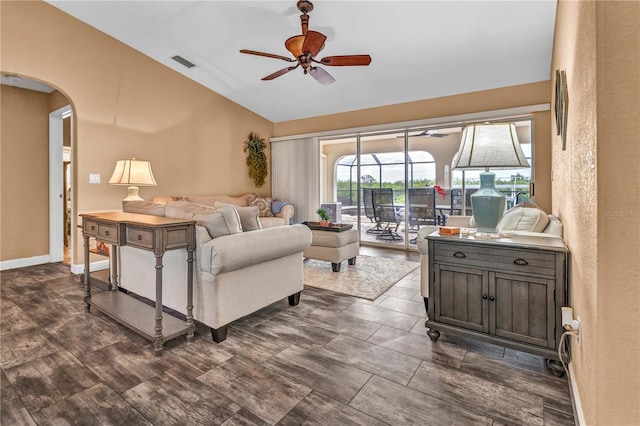 living room featuring arched walkways, visible vents, a ceiling fan, vaulted ceiling, and baseboards