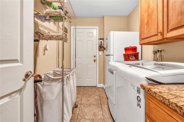 laundry area with cabinet space, washing machine and dryer, and light tile patterned floors