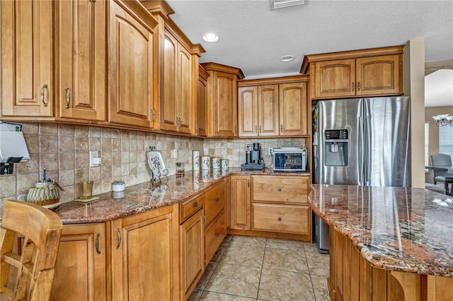 kitchen featuring brown cabinetry, dark stone counters, and tasteful backsplash