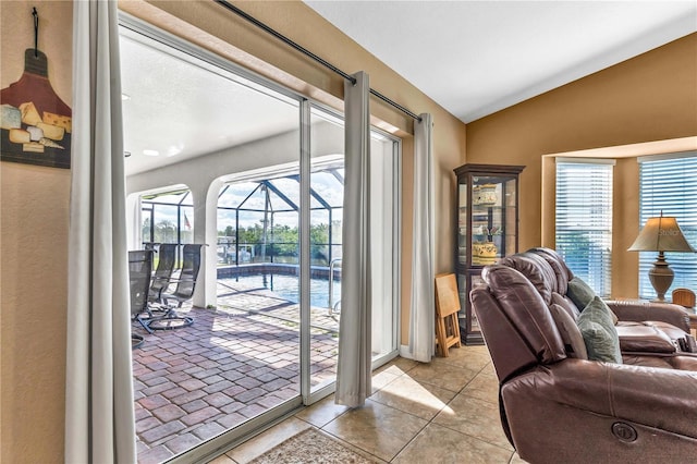 doorway to outside featuring vaulted ceiling, a wealth of natural light, light tile patterned flooring, and a sunroom