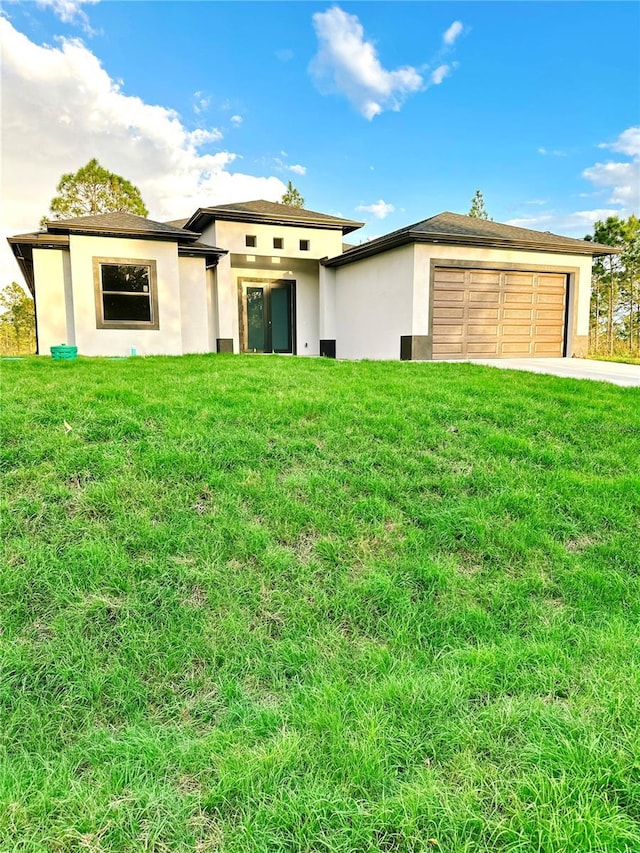 prairie-style house with concrete driveway, a front lawn, and stucco siding