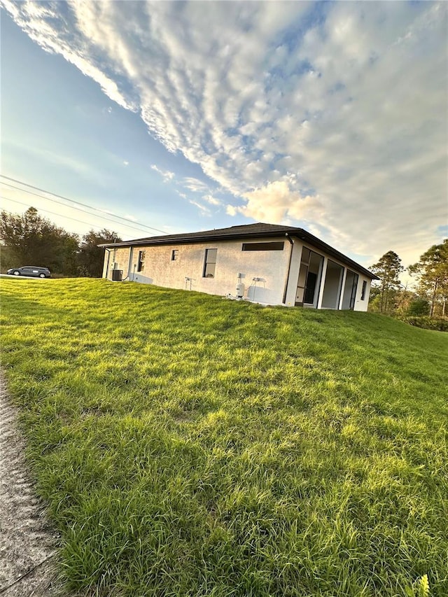 exterior space with stucco siding and a yard