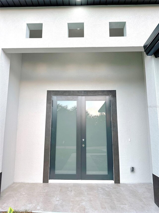 doorway to property with a patio, french doors, and stucco siding