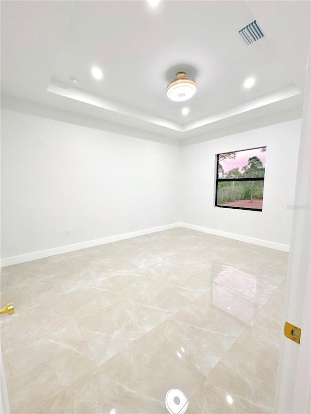 empty room featuring visible vents, a tray ceiling, baseboards, and recessed lighting