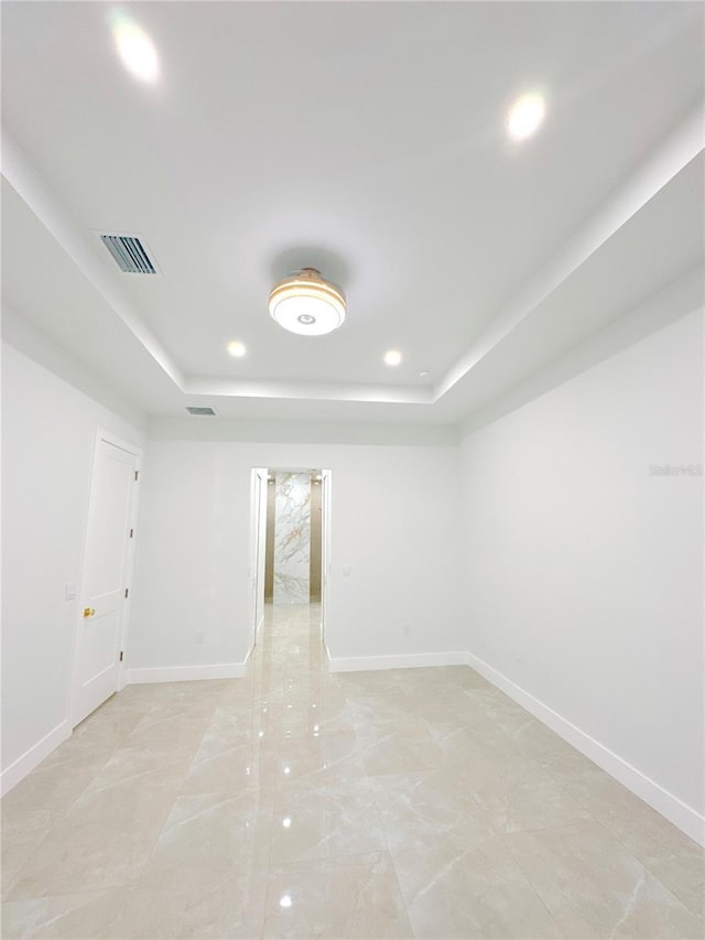 empty room with recessed lighting, a raised ceiling, visible vents, and baseboards