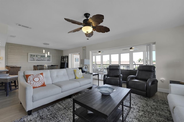 living room with baseboards, visible vents, and wood finished floors