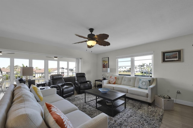 living area with ceiling fan, baseboards, wood finished floors, and a healthy amount of sunlight