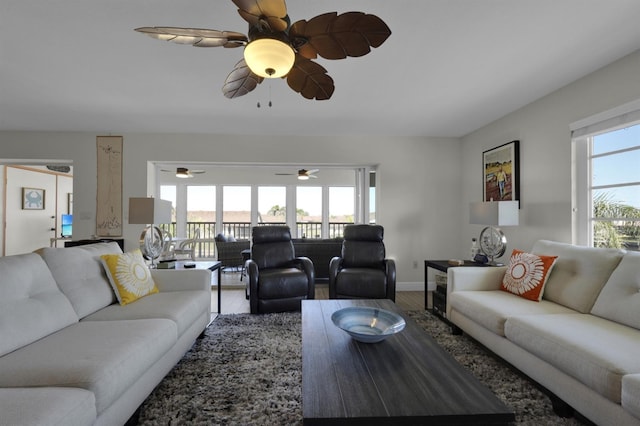 living area featuring plenty of natural light, baseboards, ceiling fan, and wood finished floors