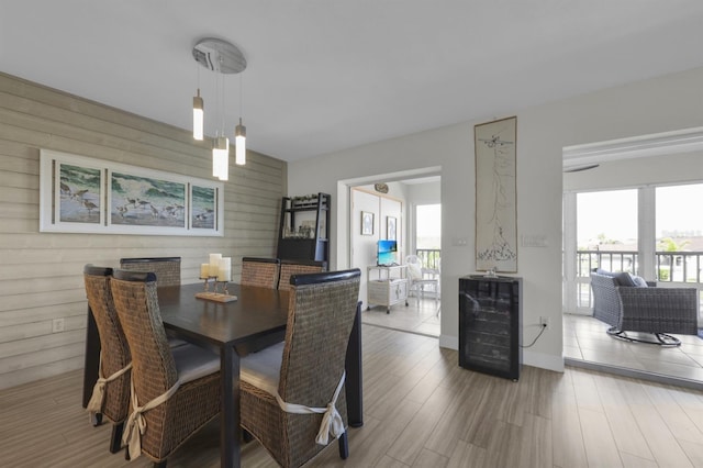 dining room with wood walls, wine cooler, a wealth of natural light, and wood finished floors