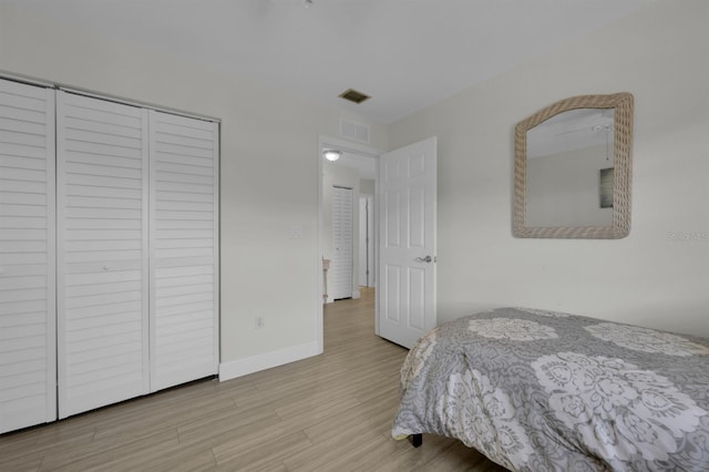 bedroom with visible vents, a closet, baseboards, and wood finished floors