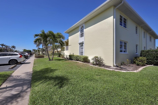 view of property exterior with stucco siding, uncovered parking, and a yard