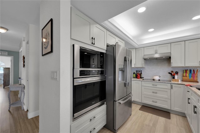 kitchen with tasteful backsplash, recessed lighting, appliances with stainless steel finishes, light wood-style floors, and under cabinet range hood