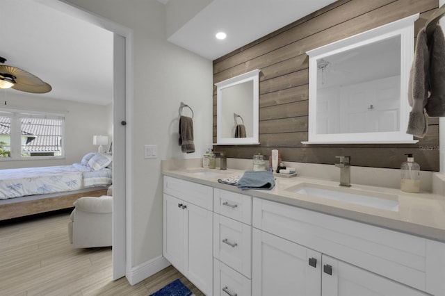 full bath featuring double vanity, a ceiling fan, a sink, ensuite bath, and wood finished floors