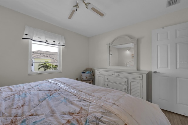 bedroom featuring a ceiling fan, visible vents, and wood finished floors