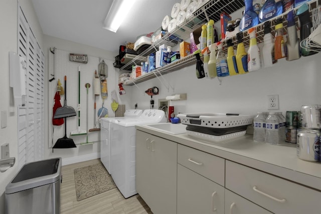 laundry area featuring cabinet space, light wood-style flooring, and washing machine and clothes dryer