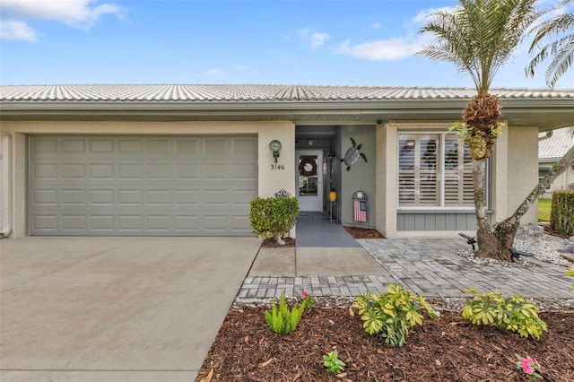 view of front of house with a garage, concrete driveway, a tiled roof, and stucco siding