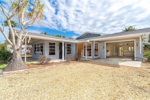 back of house with driveway, an attached garage, and stucco siding