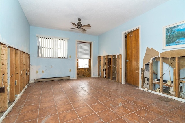 spare room featuring baseboard heating, a ceiling fan, and dark tile patterned flooring