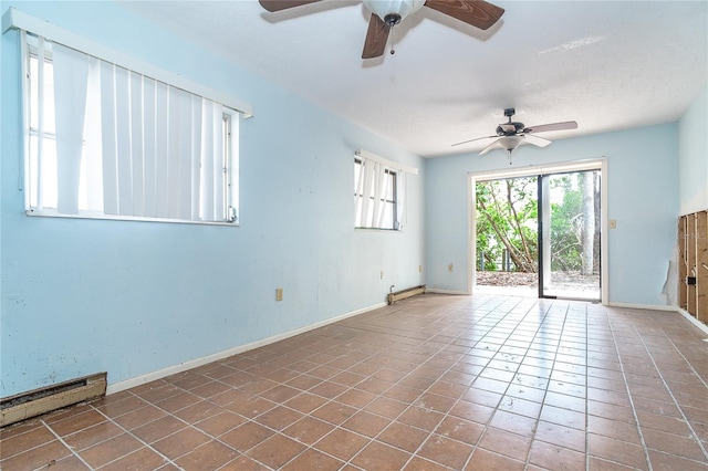 spare room featuring baseboard heating, tile patterned flooring, and baseboards