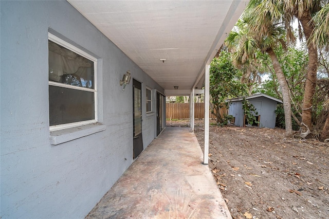 view of patio / terrace featuring an outdoor structure, fence, and a storage shed