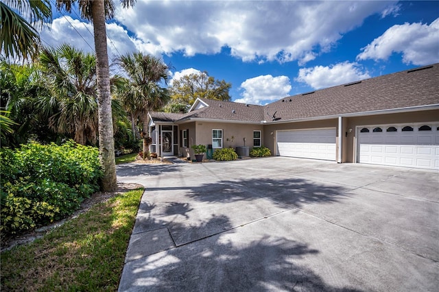 ranch-style house with driveway, central air condition unit, a garage, and stucco siding