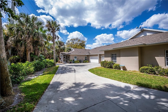 view of front of house featuring driveway, a garage, roof with shingles, a front lawn, and stucco siding