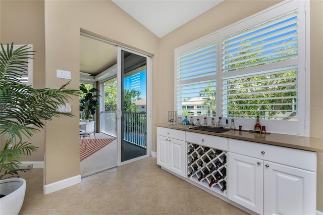 entryway with lofted ceiling, light tile patterned floors, and baseboards