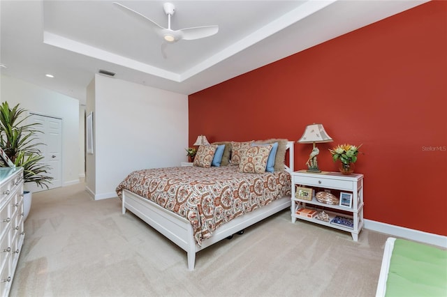 bedroom featuring carpet floors, a tray ceiling, visible vents, ceiling fan, and baseboards