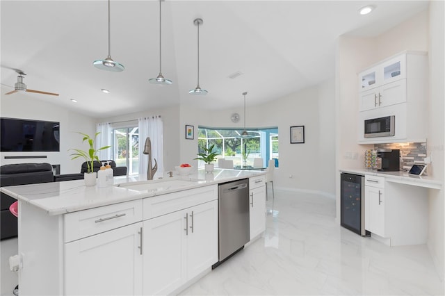 kitchen featuring wine cooler, stainless steel appliances, a sink, white cabinets, and decorative light fixtures