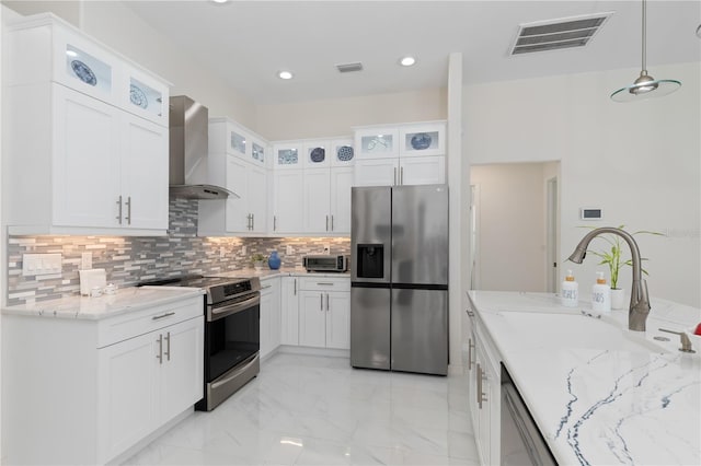 kitchen with decorative light fixtures, visible vents, appliances with stainless steel finishes, glass insert cabinets, and wall chimney exhaust hood