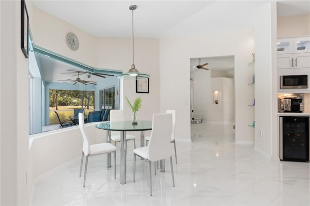 dining room featuring beverage cooler, ceiling fan, marble finish floor, and baseboards