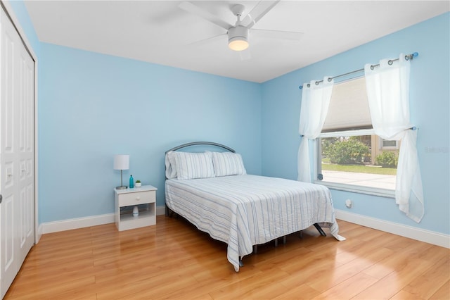 bedroom with light wood-type flooring, a closet, ceiling fan, and baseboards