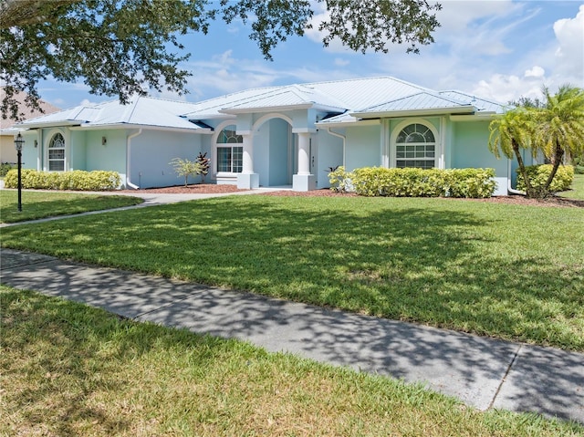 view of front of property with metal roof, a front yard, and stucco siding