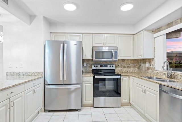 kitchen with a sink, visible vents, white cabinetry, appliances with stainless steel finishes, and decorative backsplash