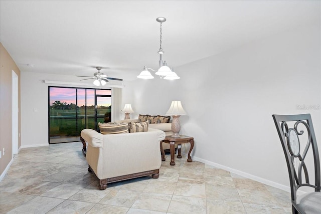 living area with baseboards and ceiling fan with notable chandelier