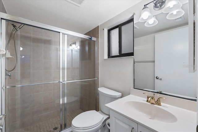 bathroom featuring visible vents, toilet, vanity, and a shower stall