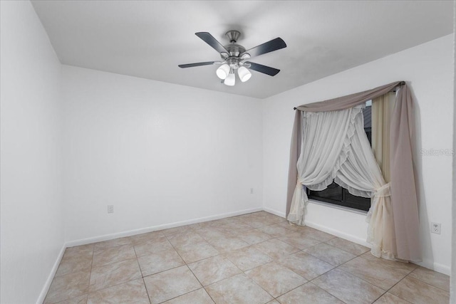 spare room featuring a ceiling fan, baseboards, and light tile patterned floors