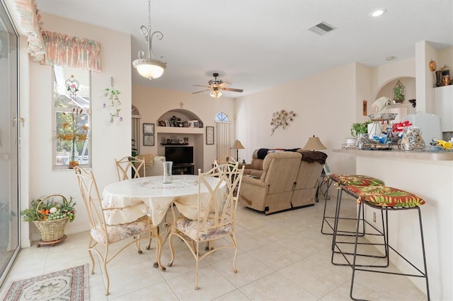 dining area with arched walkways, light tile patterned floors, visible vents, and a ceiling fan